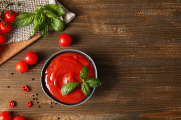 Wall Mural - Bowl of tasty tomato sauce with basil leaves and peppercorns on wooden background