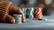 © visoot - Hand holding poker chip stack on casino table, blurred colorful chip piles in background, gambling concept, focused, anticipation