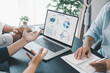 © doidam10 - Business data analysis concept with colleagues reviewing financial report on laptop, pointing at chart with growth graph, teamwork discussing statistics, planning strategy and corporate success.