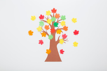 Wall Mural - Created brown tree with colorful maple leaves from application paper on light gray table background. Closeup. Making autumn decoration. Child handcraft. Top down view.
