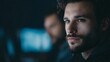 © Thares2020 - Close up portrait of a thoughtful man with piercing blue eyes looking away from the in a dimly lit modern environment with subtle blue light