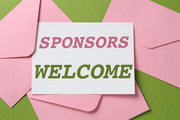 Wall Mural - Paper with phrase Sponsors Welcome and envelopes on green background, top view
