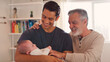 © Monkey Business - Grandfather With Adult Son Holding Baby Granddaughter At Home