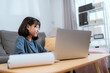 © 2B - Young woman focuses on her laptop while working in a cozy living room during the day