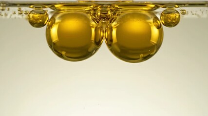 Wall Mural - Macro slow motion of golden oil drops gently separating and reforming within a transparent liquid gold, golden oil drops, golden