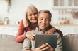 © Prostock-studio - Cheerful Mature Couple Using Digital Tablet Computer Watching Movie Together Sitting On Sofa At Home. Senior Spouses Browsing Internet Using Gadget. Technology, Retirement Lifestyle Concept