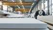 © A2Z AI  - Manufacturing plant with workers inspecting stacks of finished product on a production line, quality control, industrial setting, white panels