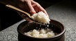 © Nur Stock - Close-up of cooked rice being scooped with a wooden spoon from a traditional ceramic pot, showcasing steaming grains