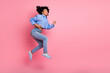 © deagreez - Young woman jumping joyfully against a pink background showcasing happiness and energy in casual modern style