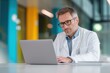 © Prazis Images - Male Doctor in a White Coat Working on a Laptop