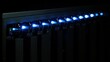 © Anda - rack. Close-up of glowing blue server rack lights creating an abstract technological pattern on a dark background. product launch decks.