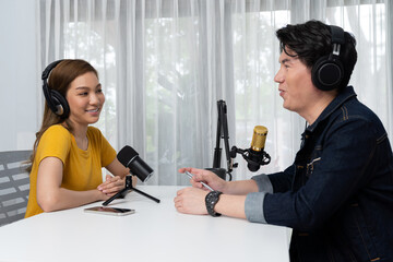 Smiling radio influencer host wearing headphone interviewing woman speaker sharing information to listeners on social media online website live streaming channel at morning at studio record. Infobahn.