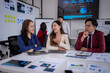 © Wasana - Asian business team analyzing charts and reports in modern office: discussing growth strategies