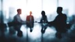 © Thares2020 - Blurred silhouettes of business professionals in a bright office meeting discussing strategy