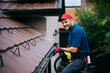 © Drazen - Happy maintenance worker cleaning gutters on roof with blower.