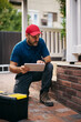 © Drazen - Home repairman using digital tablet while examining porch.