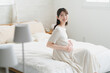 © aijiro - ベッドでくつろいでいる妊婦　ライフスタイルイメージ