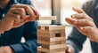 © ERWIN - Two people carefully playing a wooden block stacking game, representing strategy and risk in business.