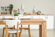 © Pixel-Shot - Wooden dining table with houseplant and wicker mats in stylish kitchen