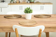 © Pixel-Shot - Wooden dining table with houseplant and wicker mats in stylish kitchen
