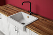 © Pixel-Shot - White counters with sink near red wall in interior of modern kitchen, closeup