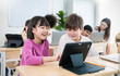 © paulaphoto - Portrait of smile teacher help elementary school children with digital tablets desks, show technology integration modern learning in classroom. Back to school, education.