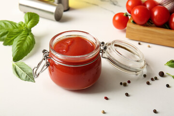 Wall Mural - Jar of tasty tomato sauce with basil leaves and peppercorns on white background, closeup