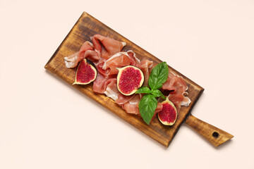 Wall Mural - Wooden board with delicious prosciutto slices, fresh fig and basil leaves on beige background