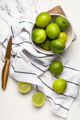 Wall Mural - Bowl with fresh ripe limes on white background