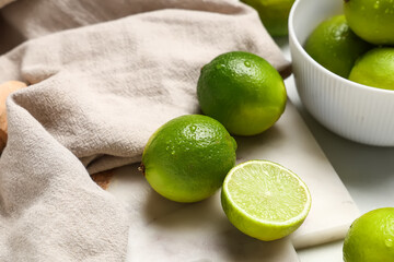 Wall Mural - Cutting board with fresh ripe limes on white background, closeup