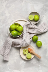 Wall Mural - Bowls and plate with fresh ripe limes on grey background