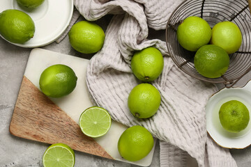 Wall Mural - Cutting board and basket with fresh ripe limes on grey background