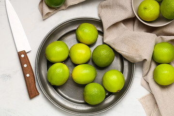 Wall Mural - Plate with fresh ripe limes on white background