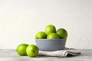 Wall Mural - Bowl with fresh ripe limes on grey table
