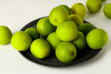Wall Mural - Plate with fresh ripe limes on white background, closeup