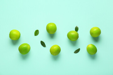 Wall Mural - Fresh ripe limes and leaves on turquoise background