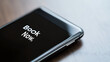 © photo for everything - Smartphone screen displaying the words 'Book Now' on a wooden surface, suggesting convenience, accessibility, and ease of digital bookings.