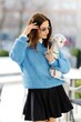 © nazariykarkhut - Stylish woman holding small dog walking in urban city