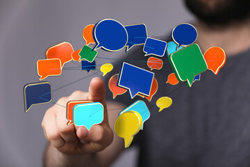A man interacts with a network of colorful speech bubbles, symbolizing digital communication and social media engagement, ideal for visual marke