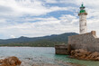 © evannovostro - A sturdy stone jetty supports a classic lighthouse overlooking calm, clear waters