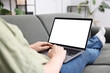 © New Africa - Woman working with laptop on sofa indoors, closeup. Mockup for design