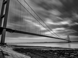 Black and white long-exposure image of the Humber Bridge stretching across the estuary at sunrise