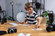 © New Africa - Choice of profession. Little boy with pictures pretending to be photographer at wooden table in studio