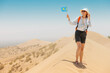 © EdNurg - Female tourist waving Kazakhstan flag while walking in Singing Barkhan desert, inside Altyn Emel National Park, during summer sunny day