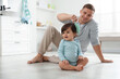© New Africa - Father brushing his baby's hair on floor in bathroom, space for text