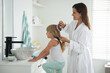 © New Africa - Mother brushing her daughter's hair in bathroom
