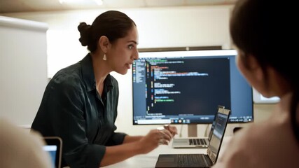 Software developer woman explains code to team. Coding, laptops, technology, team meeting, teamwork, office, programming.