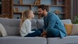 © Yuliia - Happy Caucasian family daddy and daughter talking playing laughing smiling looking each other at couch at home cute girl touching father nose funny play kid child with dad gazing game with having fun