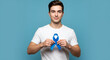 © Alt - Jovem homem segurando o laço azul do Novembro Azul  com orgulho no peito, fundo azul-claro e iluminação otimista