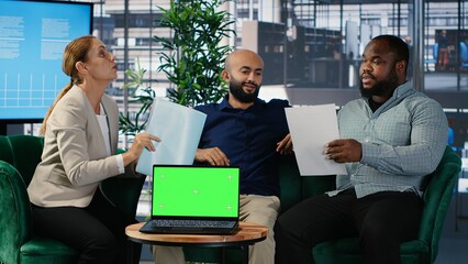 Business people negotiate to align on vision next to mockup display on laptop, using data driven insights and cultural diversity to support leadership and corporate success. Camera B.